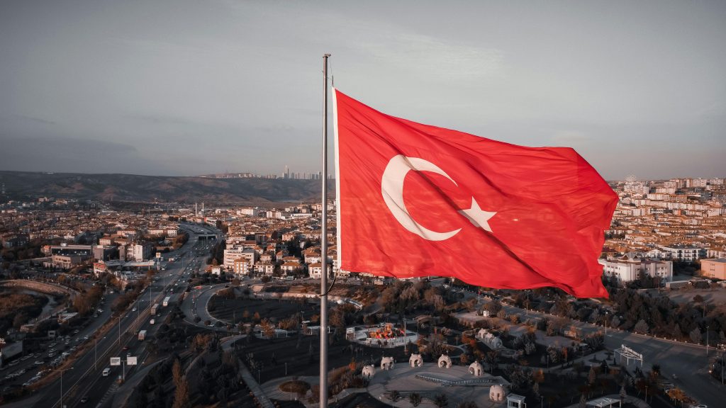 Aerial view of the Turkish flag waving with Ankara cityscape in the background.