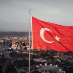 Aerial view of the Turkish flag waving with Ankara cityscape in the background.