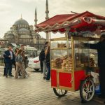 Street food vendor cart in Istanbul with mosque in background, showcasing local culture.