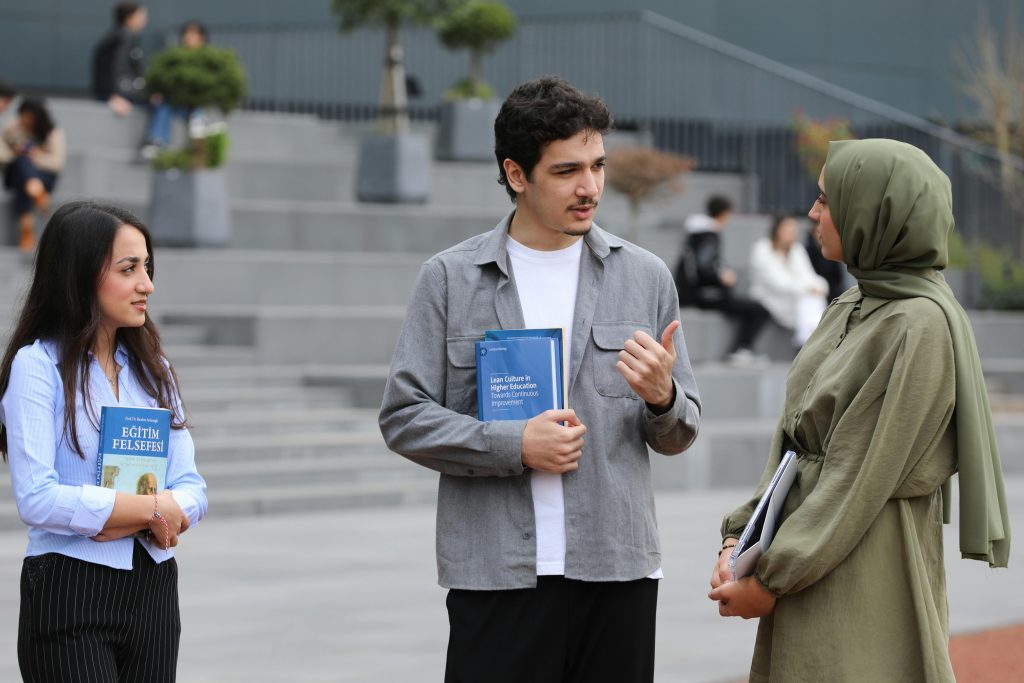 Three students engaged in conversation on campus stairs.