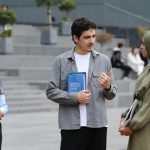 Three students engaged in conversation on campus stairs.