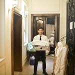 Professional hotel staff member carrying fresh linens in an elegant hallway.