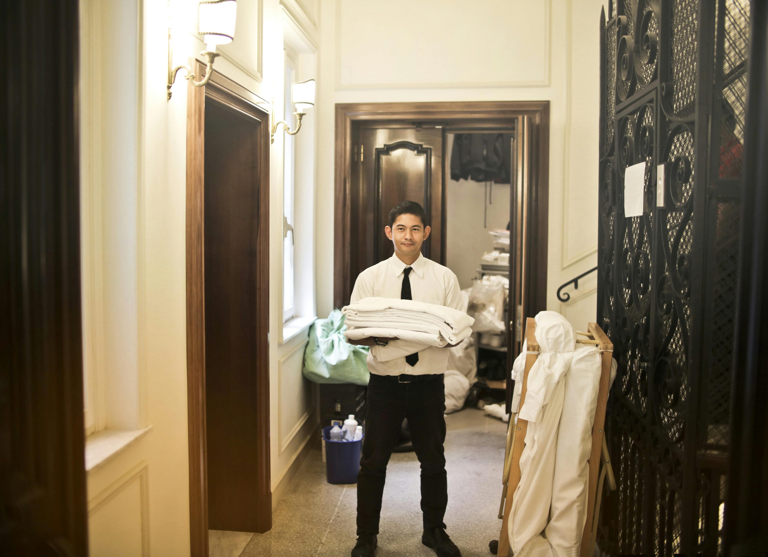 Professional hotel staff member carrying fresh linens in an elegant hallway.