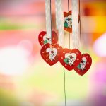 Vibrant heart-shaped decorations with love message hanging against a colorful blurred background.