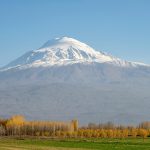 A stunning view of snow-capped Mount Ararat in Turkey surrounded by autumn foliage and clear skies.