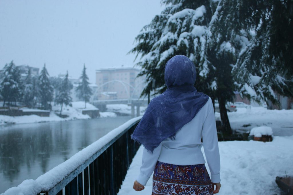 A woman in winter clothing walks along a snowy riverbank in Samsun, Turkey.