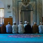 Group of men praying inside a traditional mosque in Istanbul, showcasing Islamic architecture.