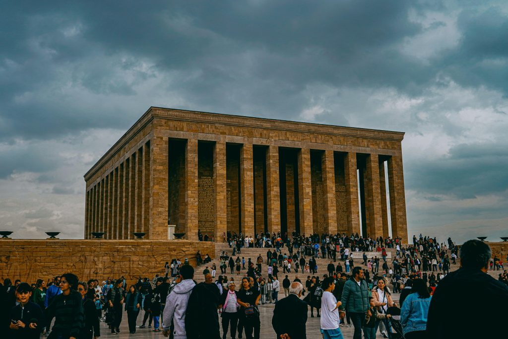 People gather at the iconic Atatürk Mausoleum in Ankara, Turkey under a cloudy sky.