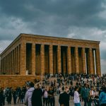 People gather at the iconic Atatürk Mausoleum in Ankara, Turkey under a cloudy sky.