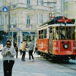 Vintage red tram surrounded by pedestrians on Istiklal Avenue, showcasing Istanbul's classic city life.