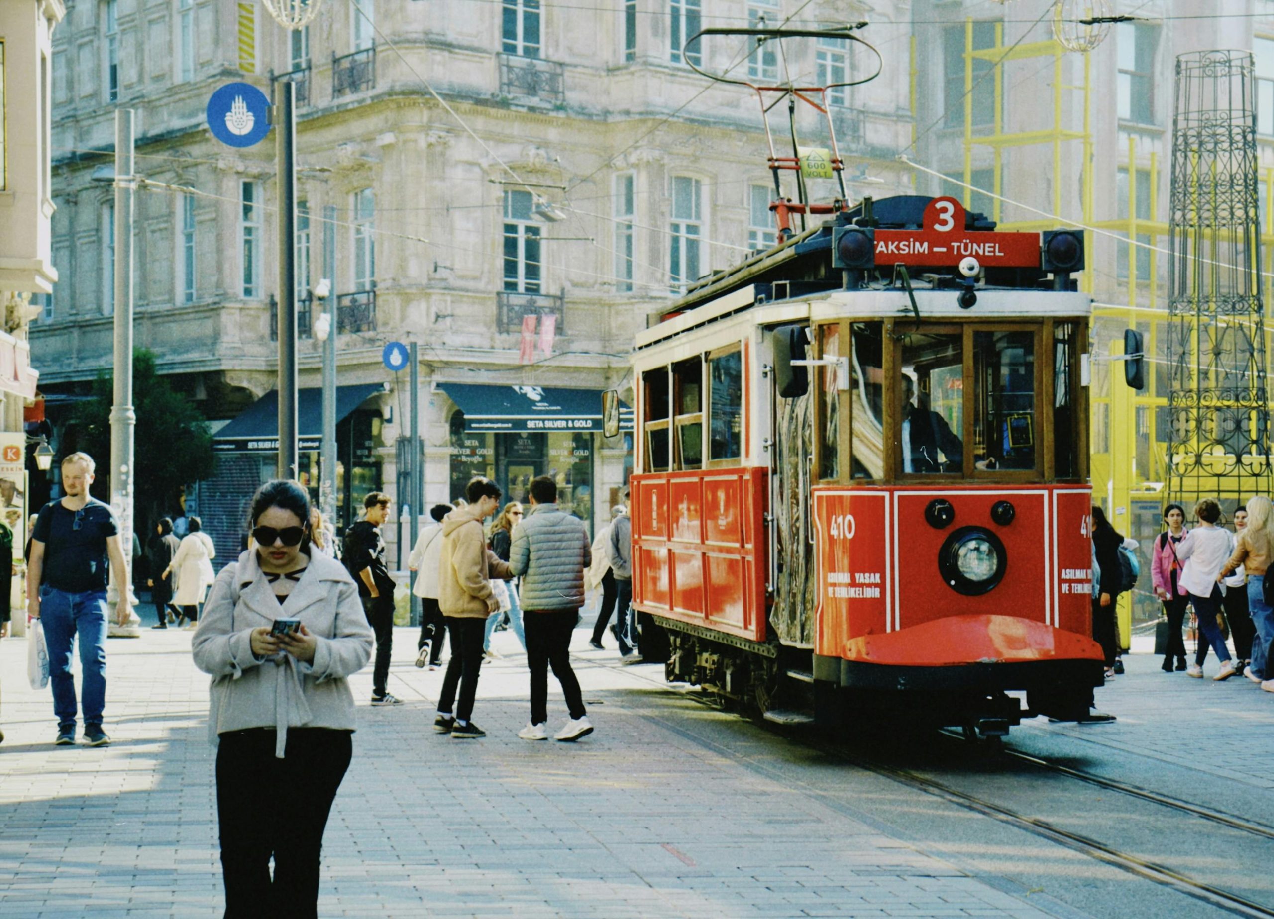Vintage red tram surrounded by pedestrians on Istiklal Avenue, showcasing Istanbul's classic city life.