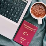 A Turkish passport beside a coffee cup and laptop, symbolizing travel and technology.