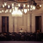 A group of worshipers praying inside a beautifully lit mosque reflecting spirituality.