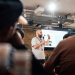 Engaging speaker presenting to an attentive audience during a tech event in London.