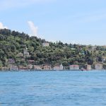 Scenic view of İstanbul's Bosphorus waterfront with lush green hills and blue waters.