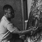 An artist skillfully paints a detailed Balinese canvas in monochrome.