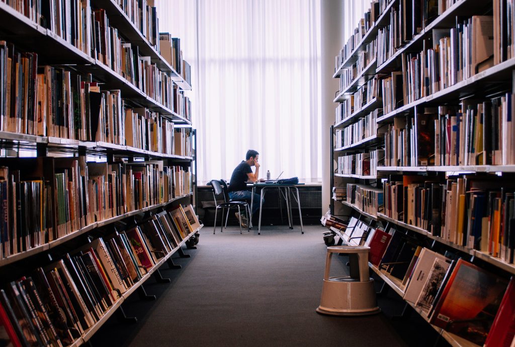 A person studies alone in a peaceful library filled with books, capturing a quiet moment of learning.