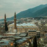 Aerial view of Bursa's iconic Grand Mosque surrounded by the cityscape and mountains.