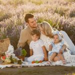 A joyful family enjoys a picnic in a blooming lavender field on a sunny summer day.