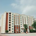 Spacious modern apartment building with a basketball court in a sunny urban setting.