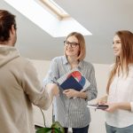 Three coworkers in an office meeting, shaking hands and discussing ideas.