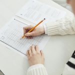 Close-up of a student filling out a multiple-choice exam in a quiet classroom setting.