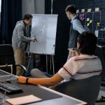 Business team in a modern office brainstorming ideas on a whiteboard. Engaged discussion and planning.
