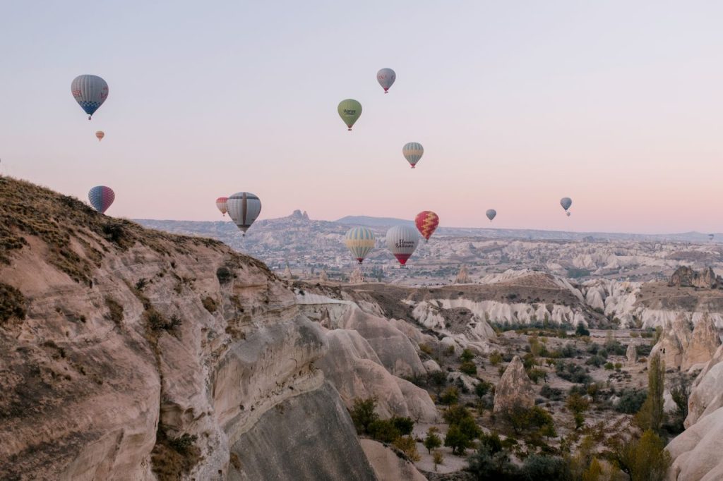 A picturesque view of hot air balloons soaring over Cappadocia's unique rock formations during sunrise.