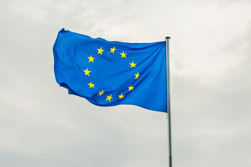 The European Union flag gracefully waving on a flagpole against a cloudy sky in Strasbourg, France.