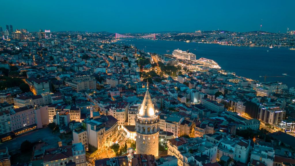 Stunning aerial view of Galata Tower with illuminated Istanbul skyline at night.