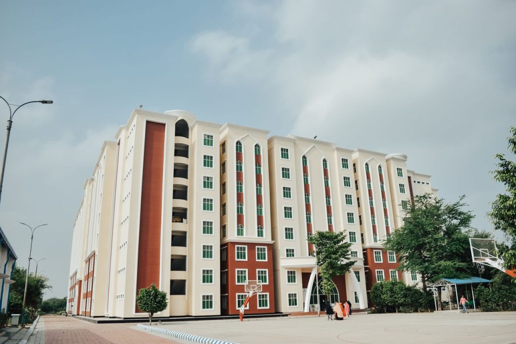 Spacious modern apartment building with a basketball court in a sunny urban setting.